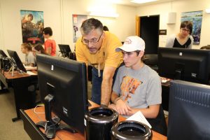 Pete Hriso, chair of the Department of Art, works with a high school student on digital animation at the Visual Art Day in October. 