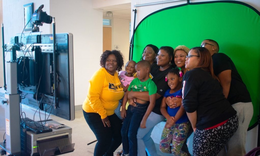 adults and children pose in a photo booth at Missouri Western's family weekend